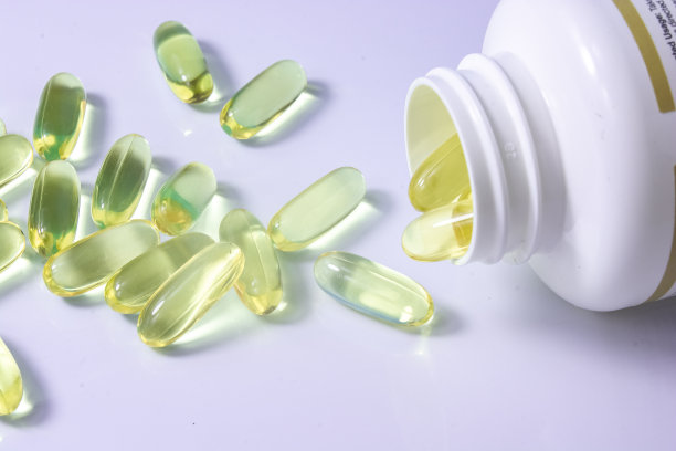 一罐欧米茄3维生素，维生素在桌子上，一个木勺欧米茄3维生素在一个蓝色的背景，一个健康的生活方式的概念，膳食补充剂，维生素，健康图片下载