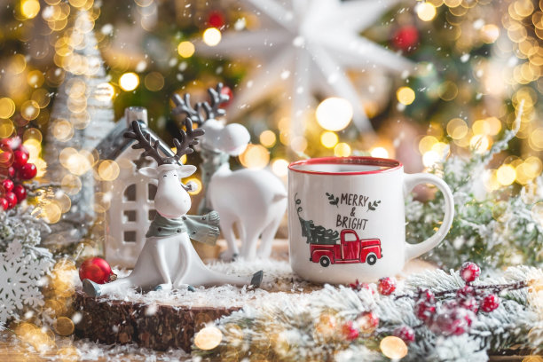 一张有可爱驯鹿的圣诞卡和一杯以美丽的焦景为背景的热咖啡。新年静物画。家庭度假的概念，温馨和舒适。图片下载