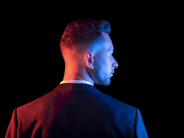 蓝色和红色灯光下一个英俊优雅的男人的肖像。男性美,时尚。有选择性的重点图片下载
