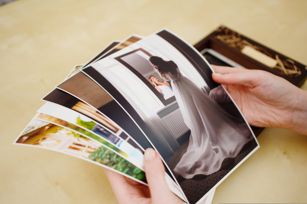 手里拿着印好的结婚照还有一个带u盘的木盒。图片下载