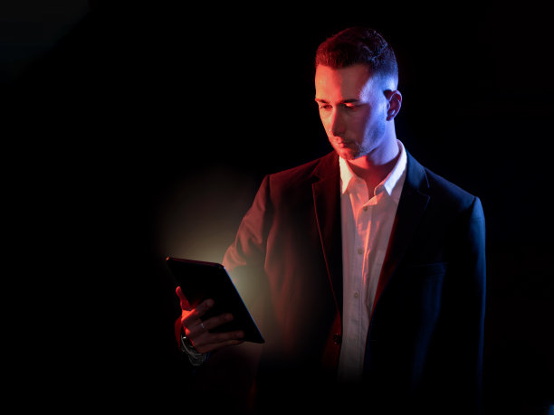 商人看着黑色背景的平板电脑。有选择性的重点图片下载