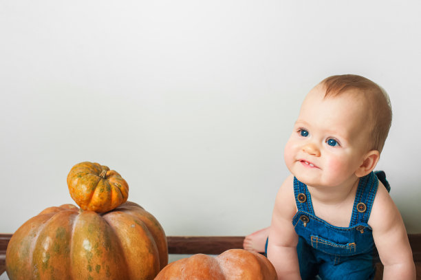 穿着牛仔工装裤和南瓜的帅哥。儿童辅食，初秋学步，万圣节，食物过敏。图片下载