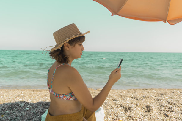在海滩上玩手机的女人图片下载
