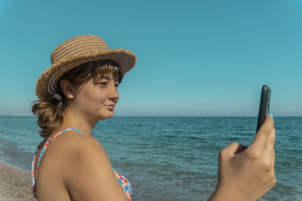 在海滩上玩手机的女人图片下载