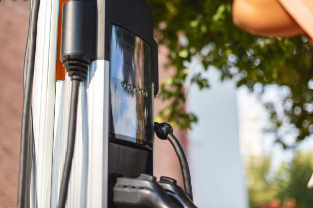 拉美裔女性在美国市中心地区的电动汽车充电站使用信用卡和电子设备支付的照片系列图片下载