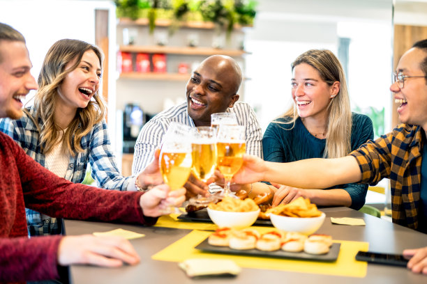 年轻花哨的人朋友喝酒和敬酒啤酒在啤酒厂酒吧餐厅-食品生活方式的概念与男人和女人有乐趣在青年旅舍-明亮的温暖过滤器与焦点中间的家伙图片下载
