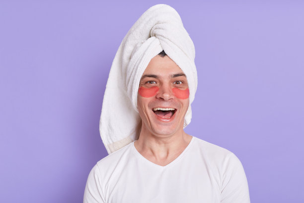 白种男子眼睛下有眼罩，裹着毛巾，兴奋地看着镜头，在家里做早上的手术，感觉很开心。图片下载