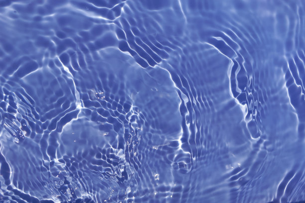 离焦模糊透明的蓝色清澈平静的水面纹理带有水花、气泡。粼粼碧水涟漪背景。游泳池的水面。蓝色的泡泡水闪闪发光。图片下载