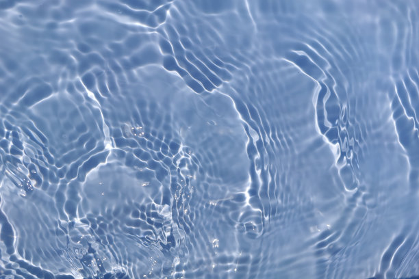 离焦模糊透明的蓝色清澈平静的水面纹理带有水花、气泡。粼粼碧水涟漪背景。游泳池的水面。蓝色的泡泡水闪闪发光。图片下载