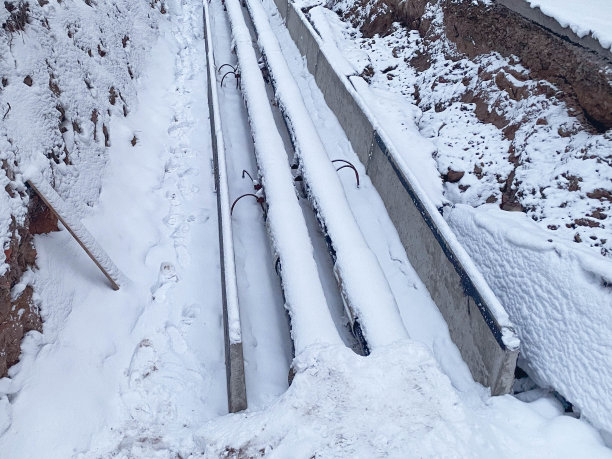 长长的，细的，黑色的，窄的管道，用于铺设管道通信。新住宅区的聚丙烯管上覆盖着一层雪。修复工作。沟渠和管道图片下载