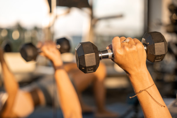 年轻女子在健身房训练，她使用重量图片下载