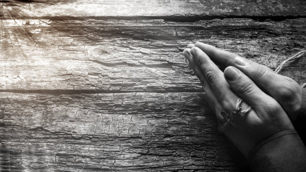 一名男子手持十字架在木制背景上祈祷图片下载