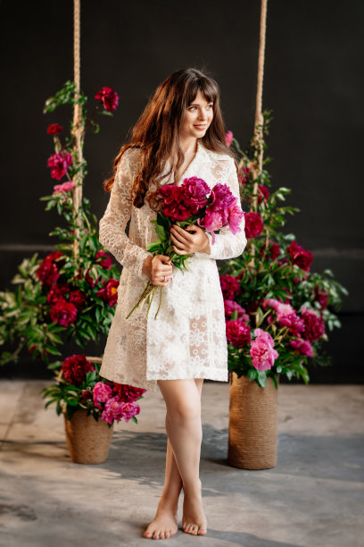 在牡丹花的荡秋千旁，一位身穿白裙的美丽年轻女子。图片下载