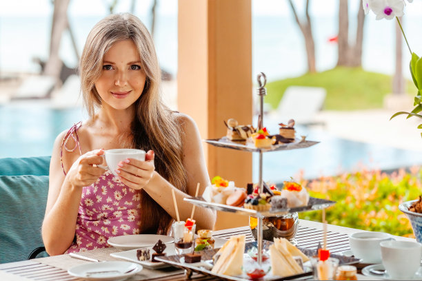 在度假村的户外餐厅里，女人坐在桌子旁，桌上摆着茶具图片下载