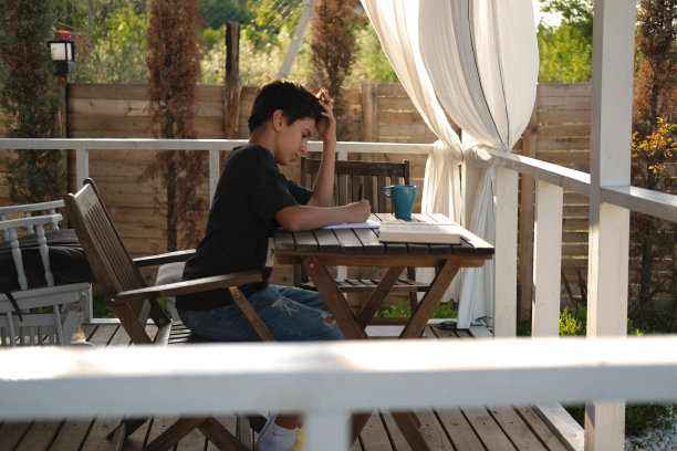 一名穿着便装的男子在田园诗般的乡村花园用笔记本电脑工作。图片下载