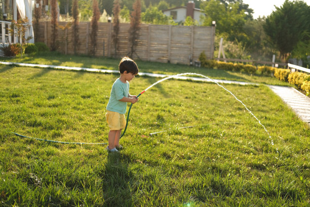 一名穿着便装的男子在田园诗般的乡村花园用笔记本电脑工作。图片下载