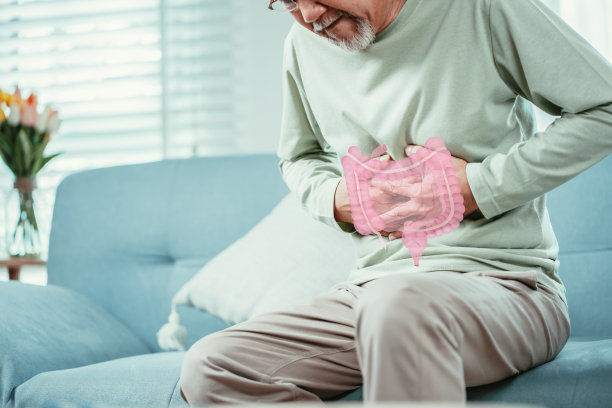 亚洲老年男子感到胃痛。年长的成年男性坐在家里客厅的沙发上摸肚子。肠道问题保健和医疗保险的概念。图片下载