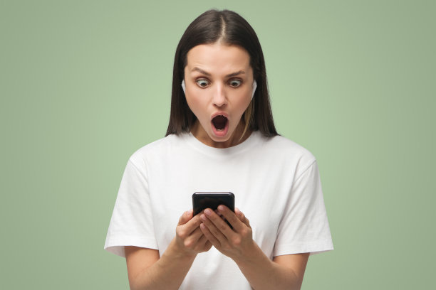年轻女子印象深刻的媒体内容从她的智能手机显示，孤立的绿色图片下载
