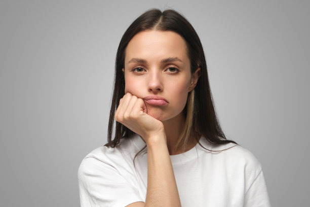 画像无聊的年轻女子与头下巴隔离在灰色图片下载