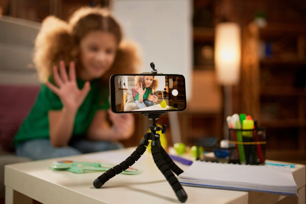 通过手机屏幕查看。可爱的小小学生为社交媒体录制视频博客。孩子的家庭活动，创造力和远程教育图片下载