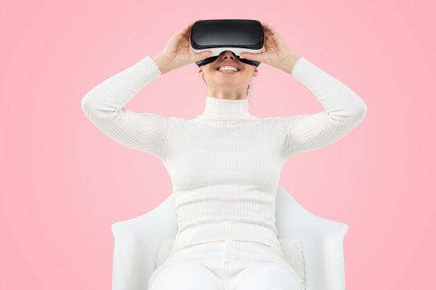 年轻的女孩探索虚拟现实的巨大机会与VR头盔的粉色背景图片下载