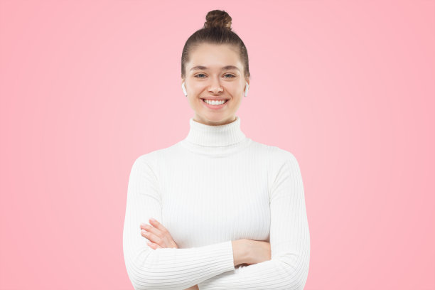 女孩盘发，双臂交叉，穿着白色毛衣，自信的微笑看着观众图片下载