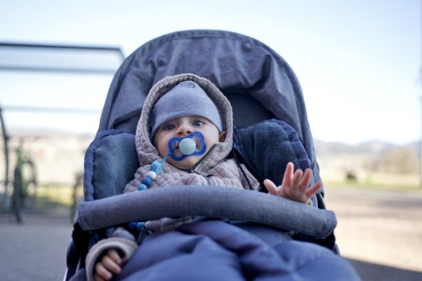 可爱的小男孩坐在外面的婴儿车里，举起左手图片下载