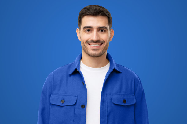 肖像微笑的年轻人在蓝色工作服衬衫蓝色背景图片下载