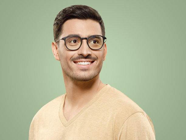 年轻英俊的微笑男人穿着米色t恤和眼镜，看着右边的复制空间图片下载