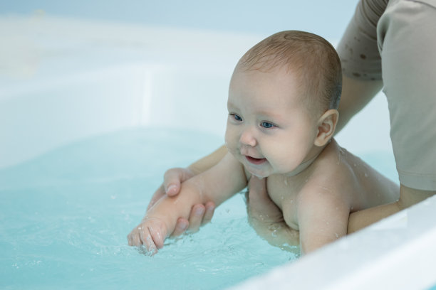 女婴喜欢在父亲的帮助下在洗澡水里游泳图片下载