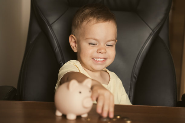 孩子把硬币放在储蓄罐里。聪明快乐的男孩在存钱罐里存钱，学习存钱。金钱、财务、保险和人的概念图片下载