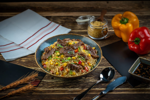 木桌上的炒饭配牛肉块和甜椒图片下载