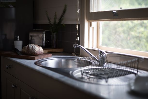 银色的厨房水槽和一块木板，靠近窗户的地方有一个面包卷图片下载