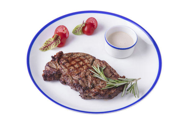 烤肉牛排配迷迭香，酱汁放在碗里，罗勒，番茄放在盘子里放在白盘子上图片下载