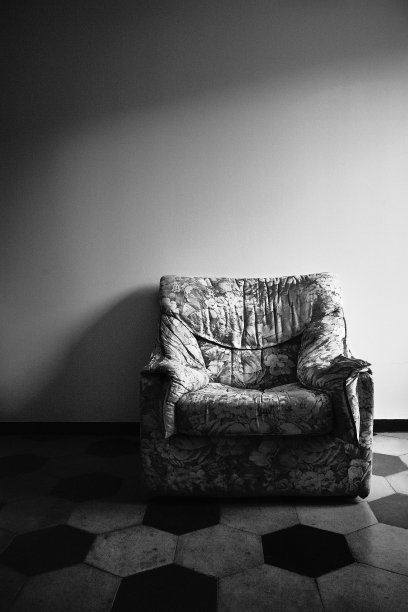 一张靠墙的空扶手椅的垂直灰度照片。图片下载