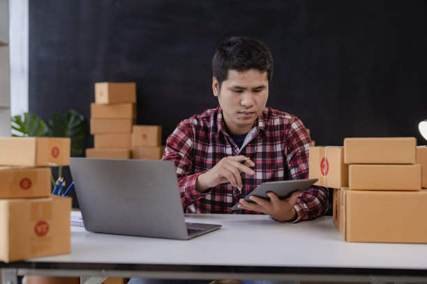 年轻的亚洲男性开始用盒子和笔记本电脑在网上销售，用来接订单和运送包裹盒，这是中小企业的经营理念。图片下载