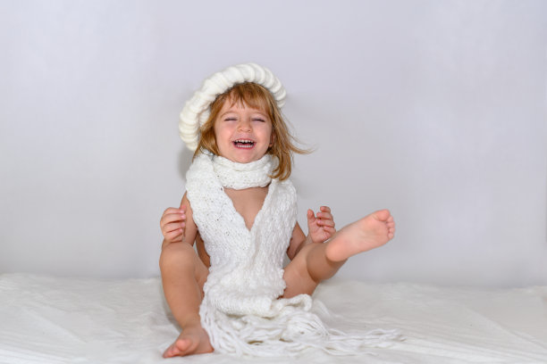 女孩笑出声来，她戴着白色的冬季贝雷帽和围巾。图片下载