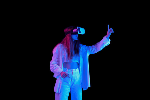 年轻美丽的女孩的肖像摆着VR眼镜孤立在黑色背景在蓝色霓虹灯图片下载