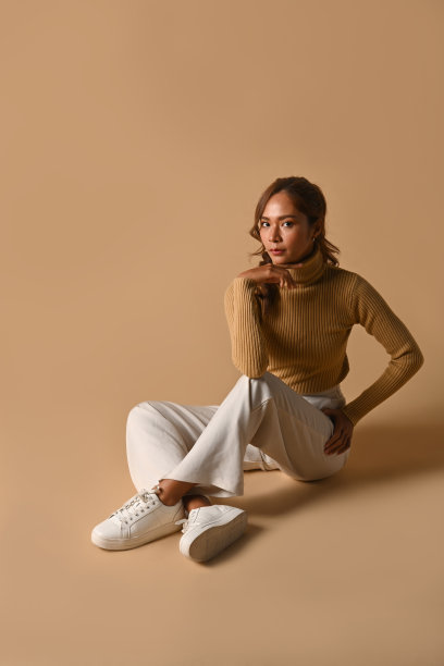 美丽的女人穿着温暖的毛衣摆姿势在米色的工作室背景。时装工作室照片，秋冬概念。图片下载