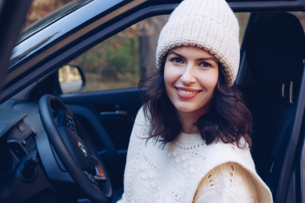年轻漂亮的褐发女子坐在车的方向盘后面图片下载