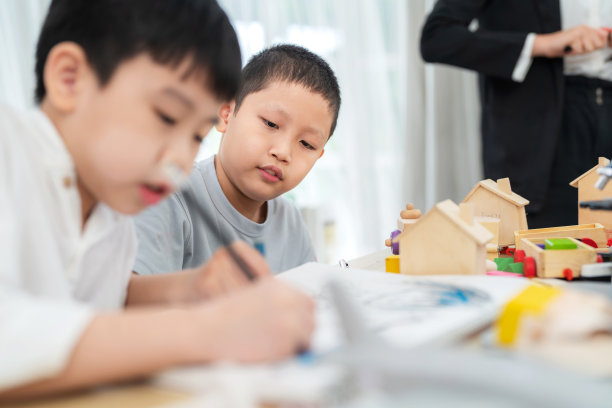 年轻的亚洲男孩坐在小学的教室里微笑。在有临摹空间的绘画课上学习和学习。在课堂上看着他的朋友画画和高兴。学术和返校理念图片下载