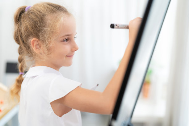 侧视图年轻的白人漂亮的女孩站在前面的班级和绘画与黑色钢笔在白板上的复制空间。在学校的课堂上创造自己的风格。儿童教育和返校理念图片下载