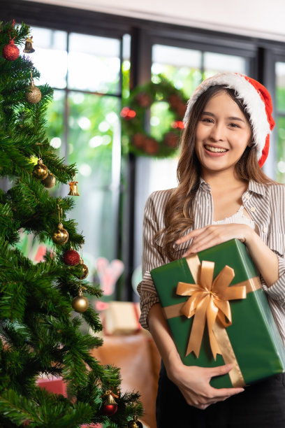 兴奋的亚洲女人在家里收到女朋友的惊喜礼物。给了一份礼物。亚洲妇女装饰彩球圣诞树在圣诞节节日冬季季节性庆祝图片下载