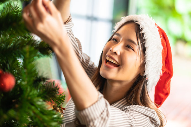 兴奋的亚洲女人在家里收到女朋友的惊喜礼物。给了一份礼物。亚洲妇女装饰彩球圣诞树在圣诞节节日冬季季节性庆祝图片下载
