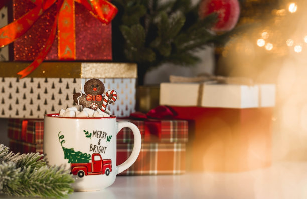 礼品盒、一杯热可可、棉花糖和一个姜饼人放在客厅室内的桌子上。2023年圣诞和冬季假期的温馨概念。图片下载