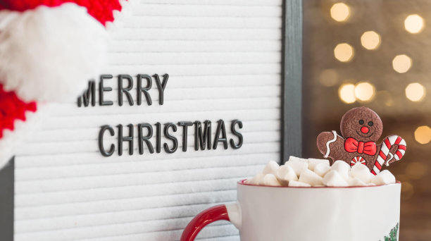 一个写着“圣诞快乐”的牌子，圣诞老人帽子，一杯热可可，棉花糖和姜饼人，背景是一个美丽的bokeh。温馨的新年和寒假概念。图片下载