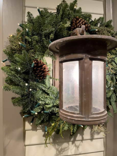 松枝与松果圣诞花环周围的外部门廊灯在晚上图片下载