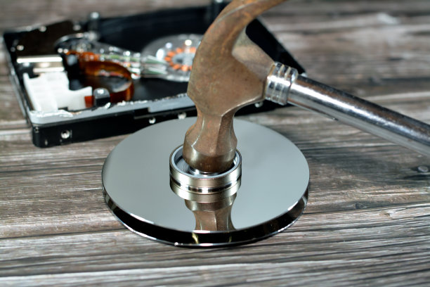 硬盘盘片和主轴电机上的钢锤，硬盘驱动器拆卸损坏组件，计算机维护，恢复，数据擦除，数据销毁软件概念图片下载