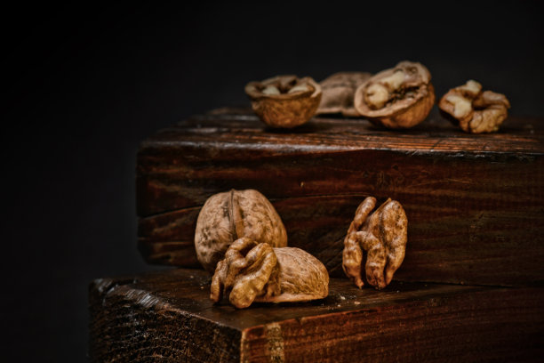 黑色孤立的背景上有半个裂开的核桃。胡桃壳在深棕色的木制背景。乡村背景。有选择性的重点。图片下载