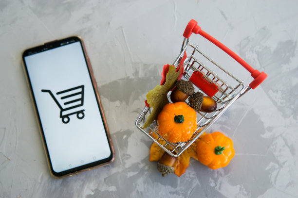 2020年9月29日，俄罗斯特维尔，智能手机和购物车，混凝土背景。在网上商店工作的概念。促销，折扣和网络星期一。图片下载